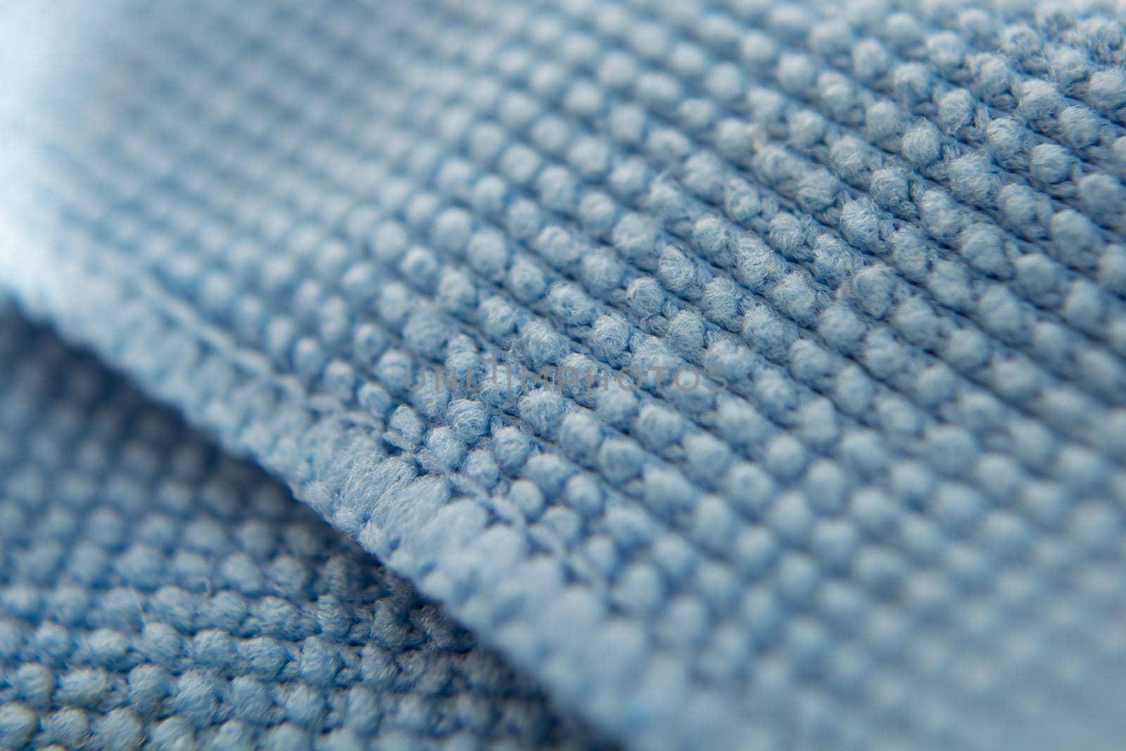 Blue cloth for cleaning the screen of the phone, tablet, TV, glasses. Microfiber structure. Selective focus. Macro filming.