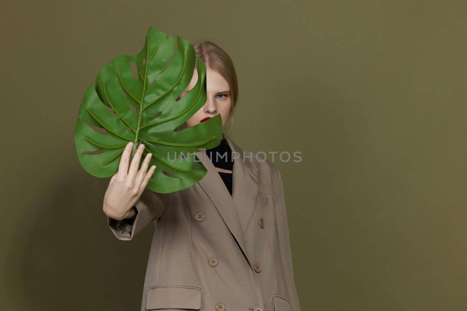 portrait of a woman red lips palm leaf charm fashion green background. High quality photo