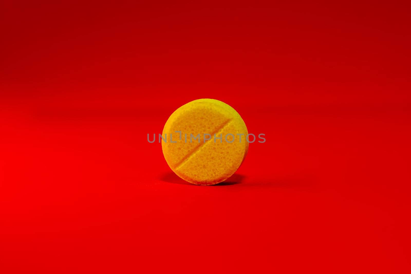 Yellow one pill on a bright red background close-up. Place for your text. Selective focus. Healthcare and medical concept.