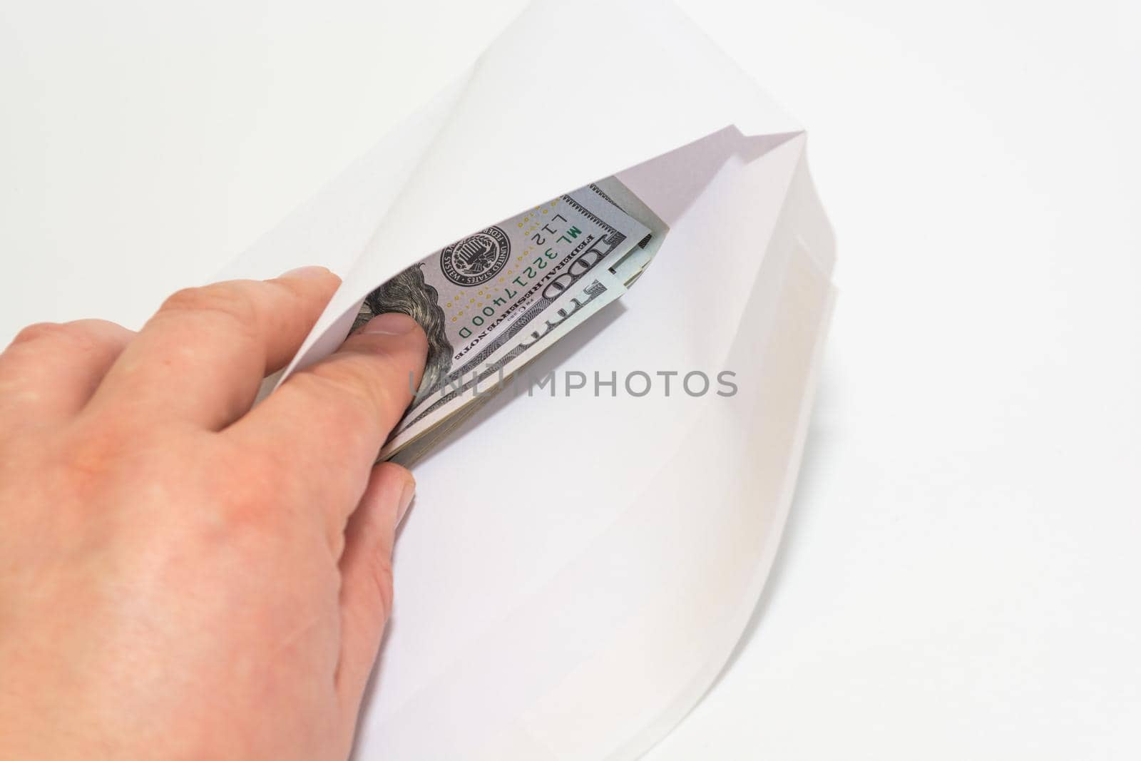 The man pulls out the money dollars from the white envelope with his fingers. White background. Selective focus.