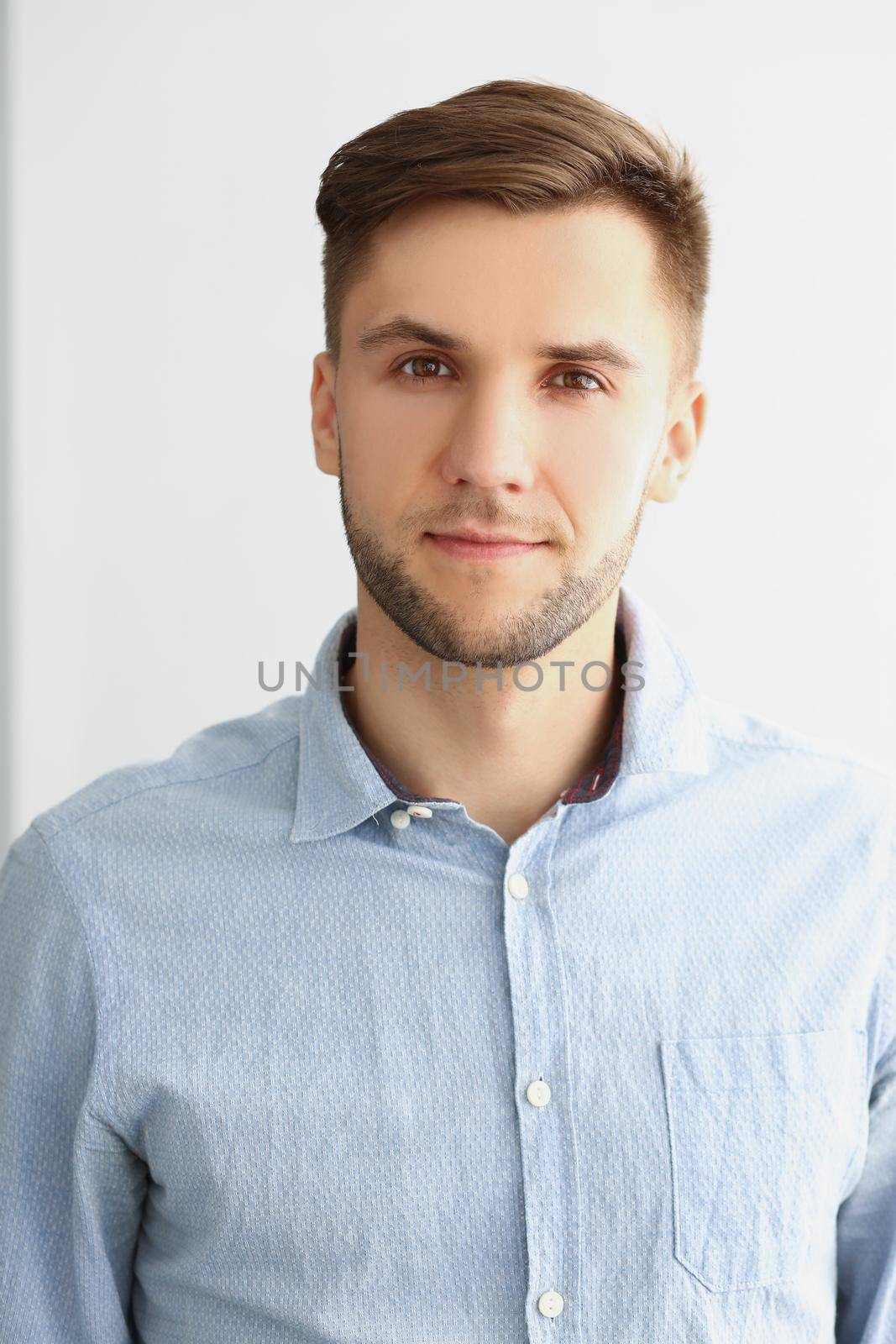 Portrait of successful young man in stylish grey shirt, presentable guy posing on white background. Confident man pose for picture. Success, status concept