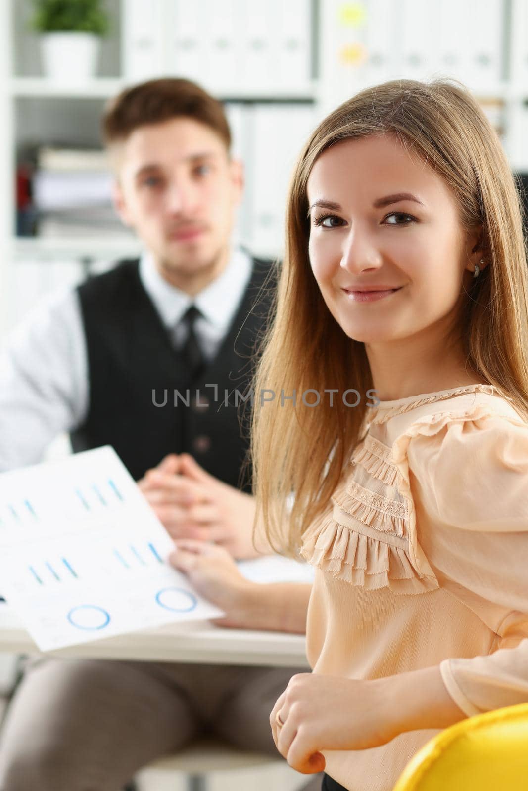 Portrait of beautiful smiling cheerful girl at workplace look in camera with male colleague. White collar worker at workspace. Business, meeting concept