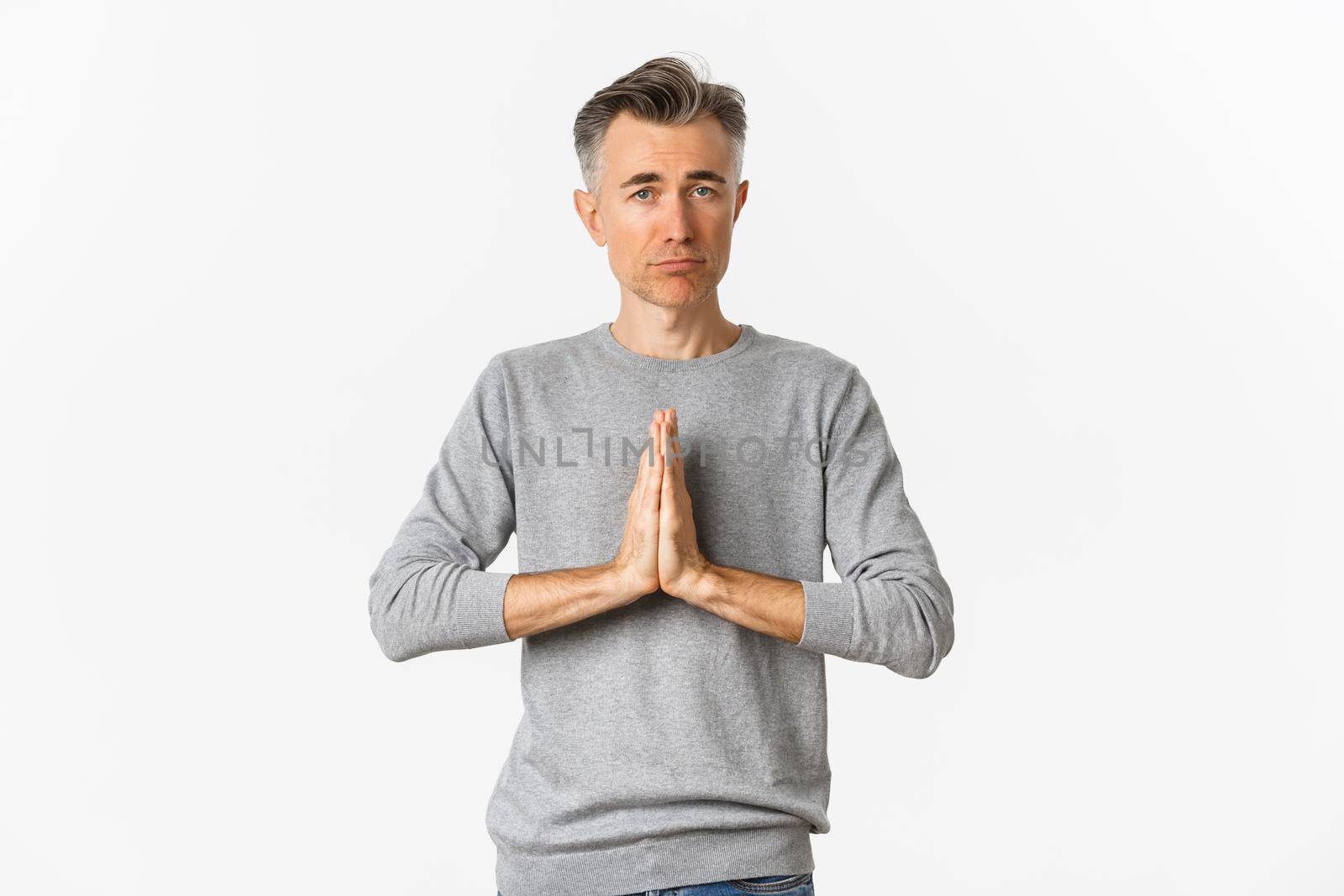 Image of sad middle-aged man begging for help, need something and asking for favour, standing over white background.