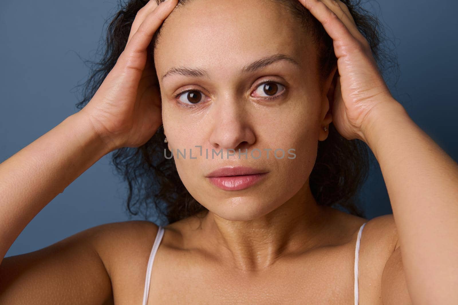 Close-up portrait of middle aged woman with no make-up and wet skin looking at camera while washing her face, taking care of her beauty and skin. Freshness, purity, cleanse, removing make-up concept by artgf