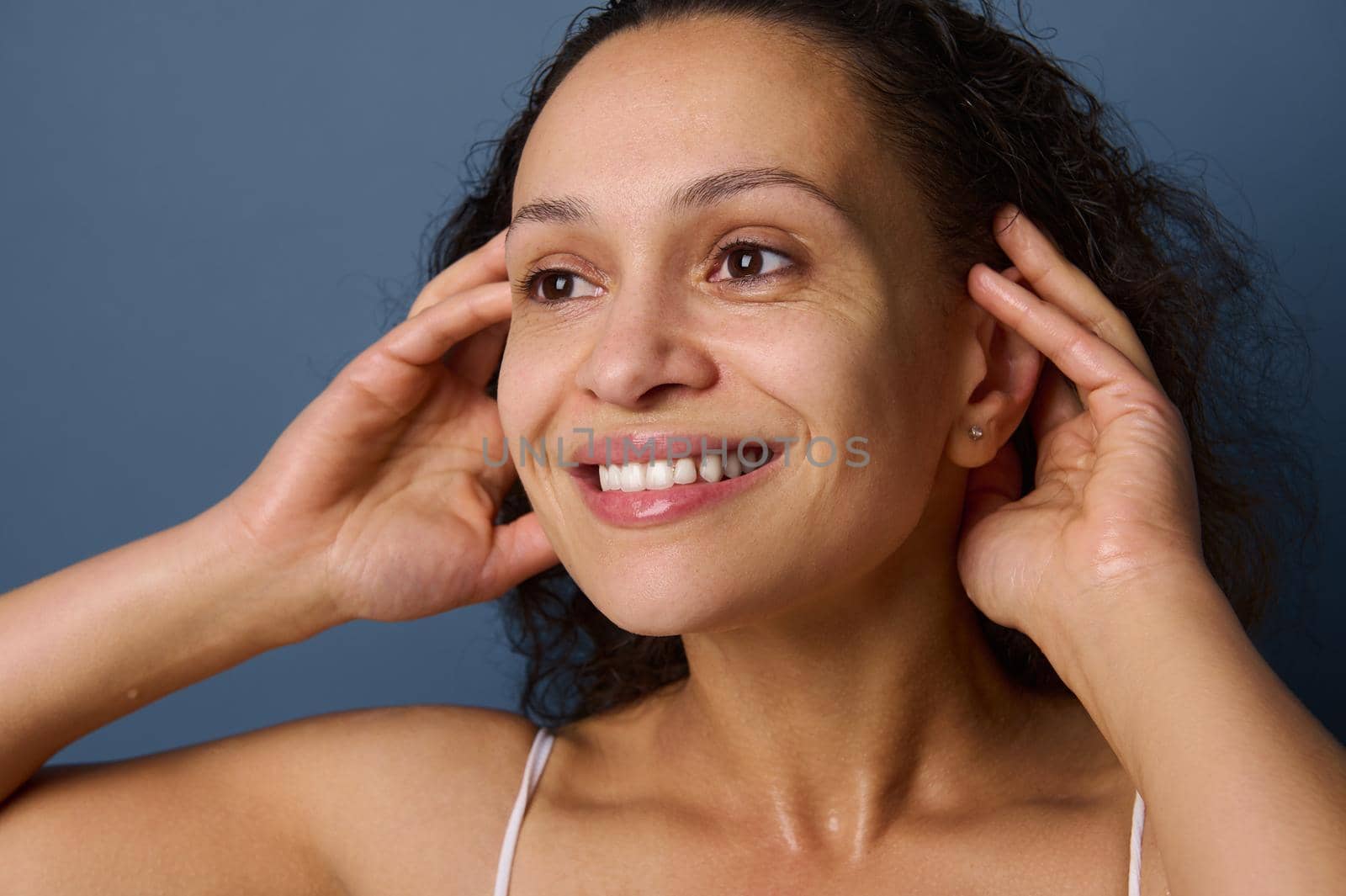 Close-up portrait of middle aged woman with no make-up and wet skin smiles toothy smile while washing her face, taking care of her beauty and skin. Freshness, purity, cleanse, removing make-up concept by artgf