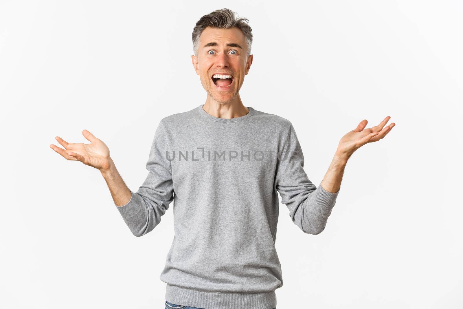 Image of shocked and frustrated man spread hands sideways, shouting and looking upset with something bad happened, standing over white background.