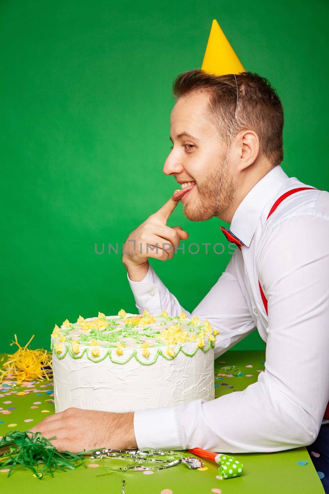 Man tasting birthday cake on green background by Julenochek