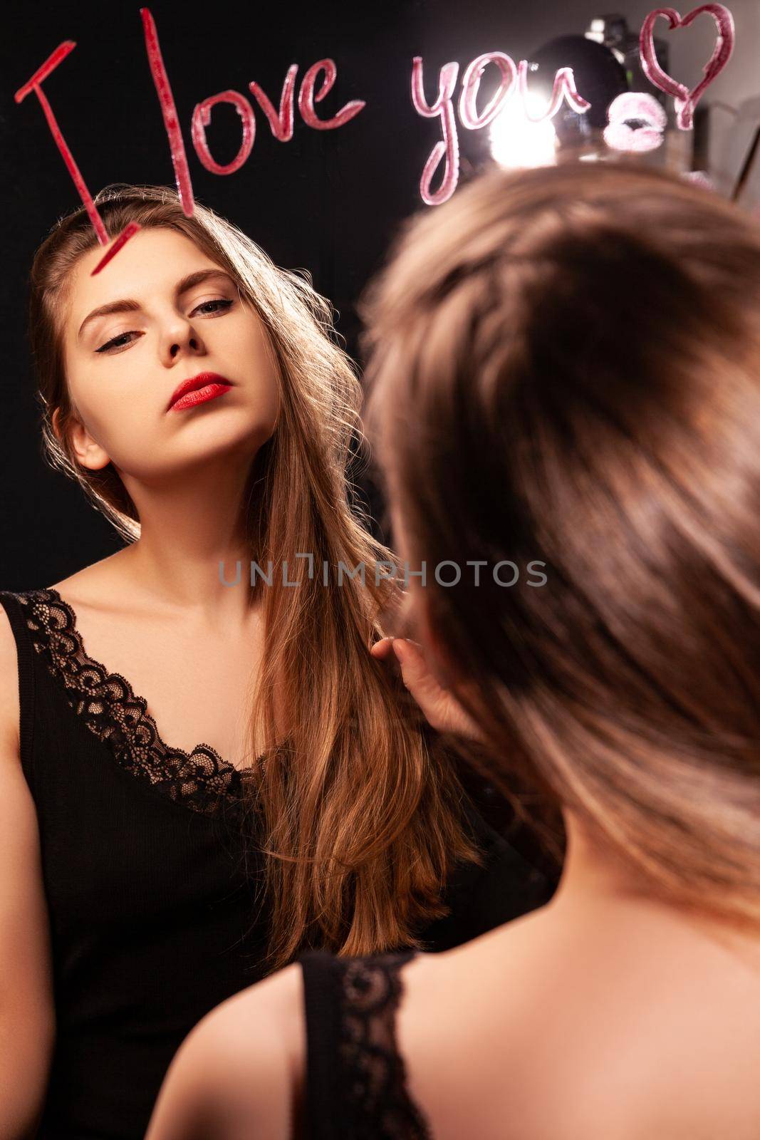 Confident female in black dress and with red lips reflecting in mirror with inscription I Love You