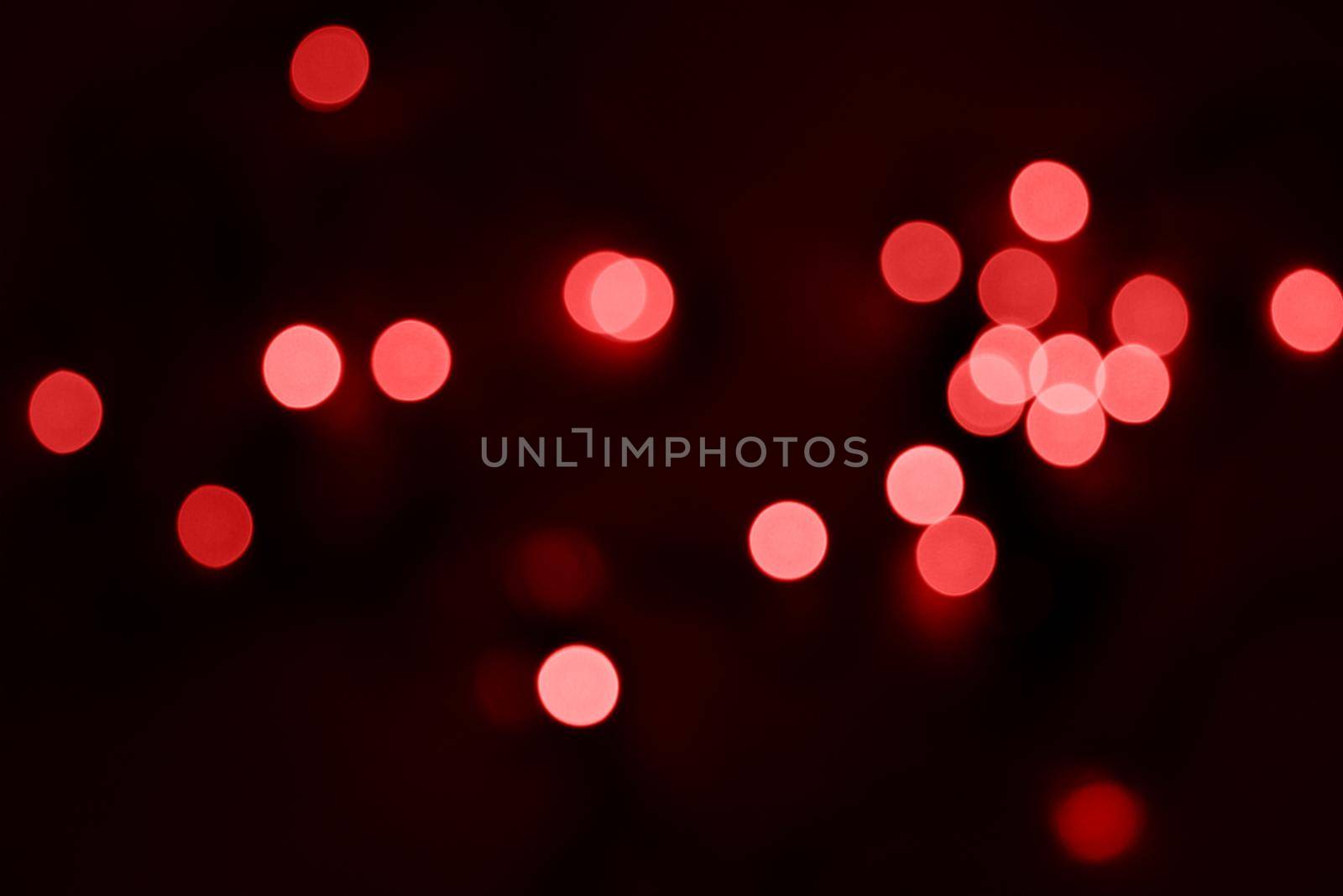 Defocused bokeh lights on black background, an abstract naturally blurred backdrop for Valentine's Day or birthday party. Festive light texture. Pink and red garland in blur. Overlay effect for design