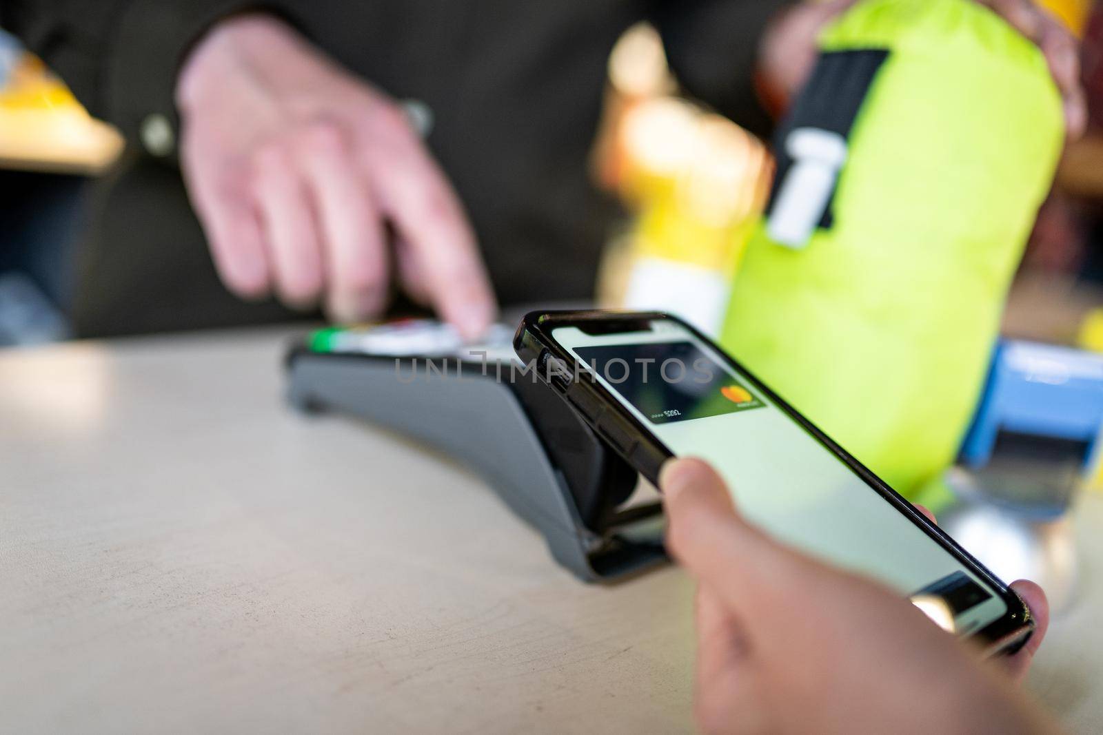 Shopping with mobile phone payment. Customer using contactless payment. Female hand paying with NFC technology on phone. Paying contactless with digital wallet. Pay by card on NFC payment terminal.