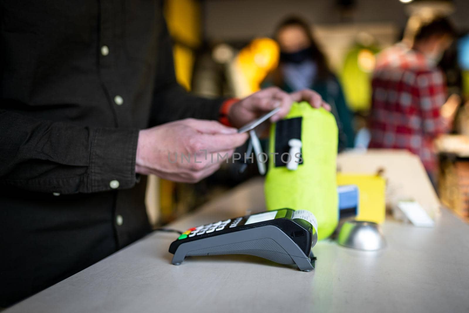Man holds payment terminal while holding receipt for completing a purchase. Hands close up and side view. Concept of NFC, business and banking transaction. Close up of payment device, card machine.