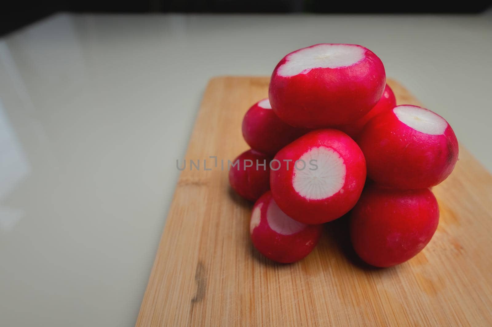 Close-up of partially peeled radishes in a pile on a wooden board. Vegetarian salad ingredient. Vegan food by yanik88
