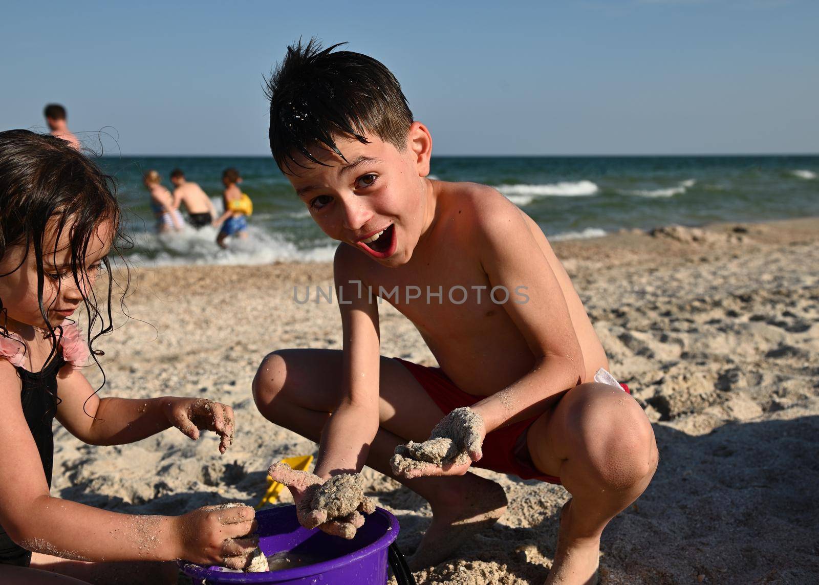 Little children playing at the sandy beach. Adorable kids building sandy castles. Focus on handsome funny boy enjoying summer holidays at the island by artgf