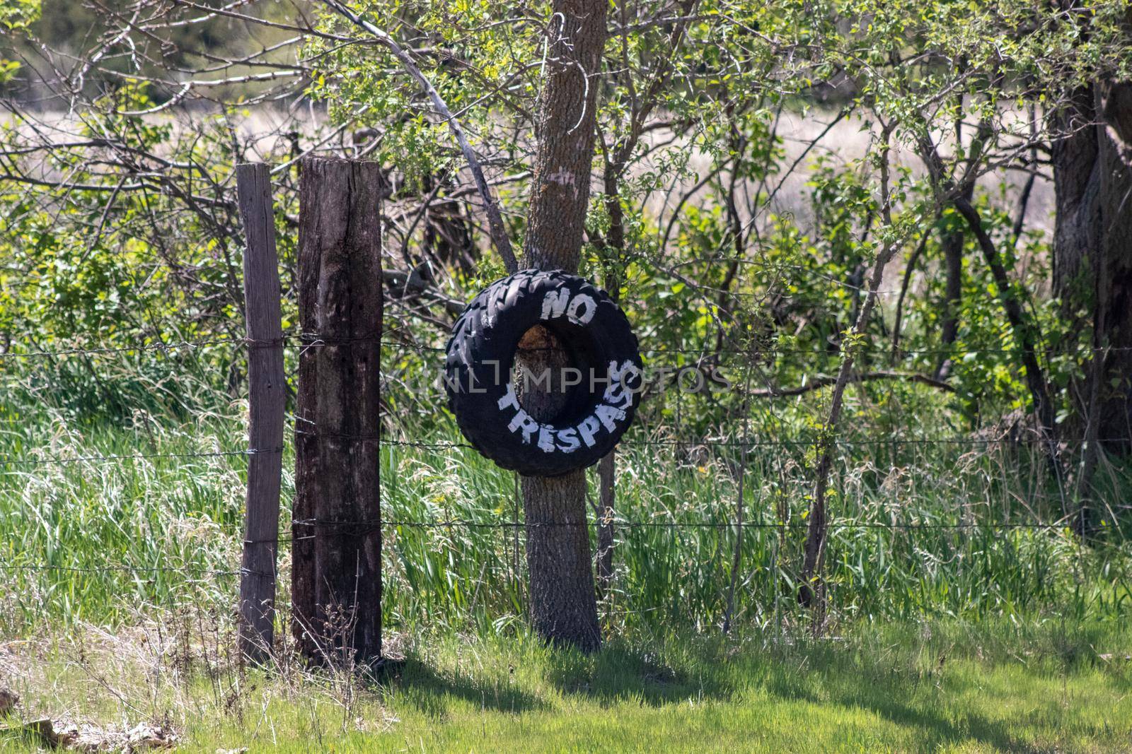 No Trespassing tire sign on barb wire fence . High quality photo