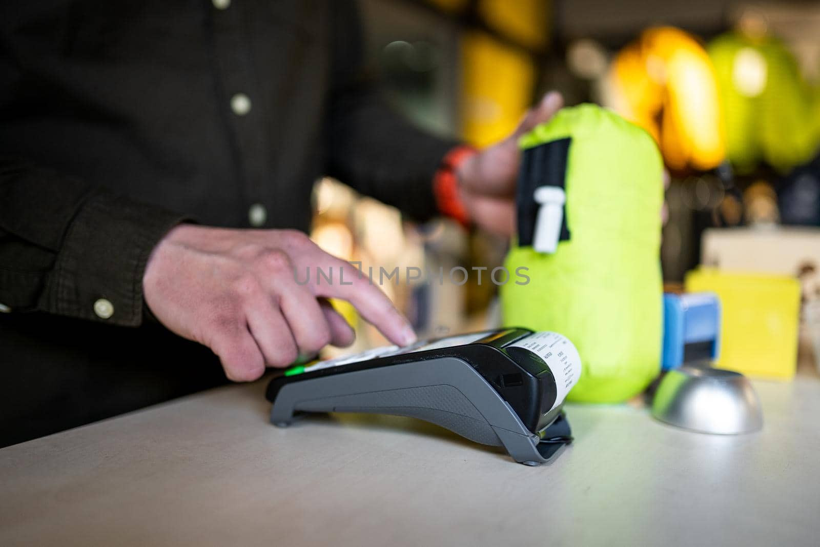 Man holds payment terminal while holding receipt for completing a purchase. Hands close up and side view. Concept of NFC, business and banking transaction. Close up of payment device, card machine.