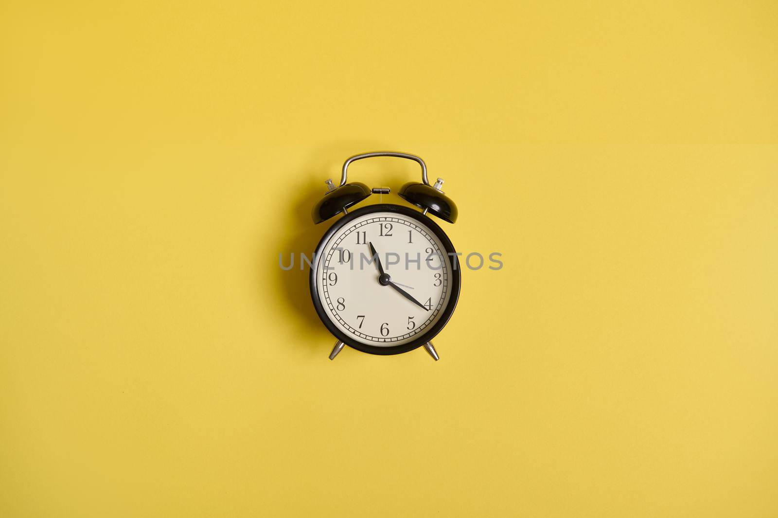Flat lay of an alarm clock, on yellow background with space for text. Concept of checking time, time management, business and events by artgf