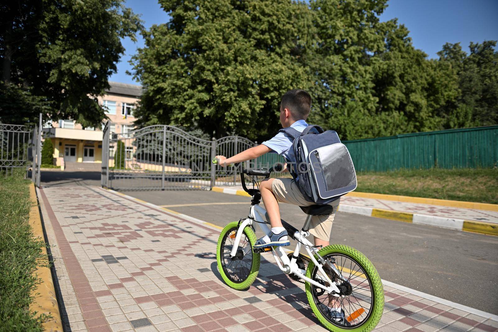 Rear view of a child on a bicycle in early morning. Boy on bike in the city by artgf