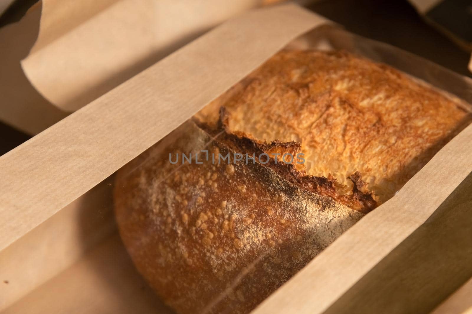 Closeup shallow depth of field handicraft bread in a paper semi transparent bag. Copy space. Place for your logo production of bread.