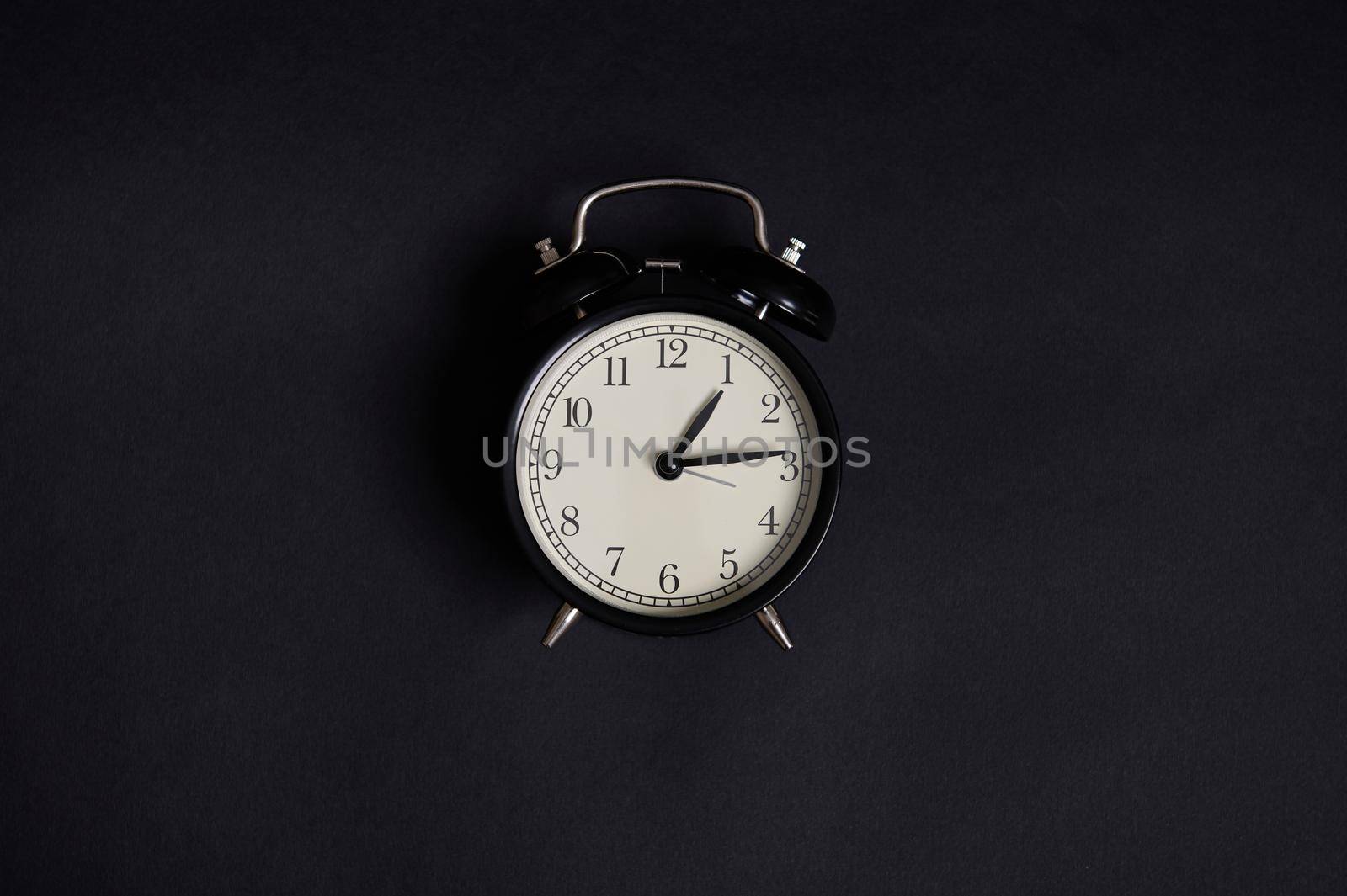 Monochrome composition with a vintage alarm clock on black background with copy space to add text. Back to School and Teachers Day Concepts, Business, Organization, Time Management. Flat lay. Top view by artgf