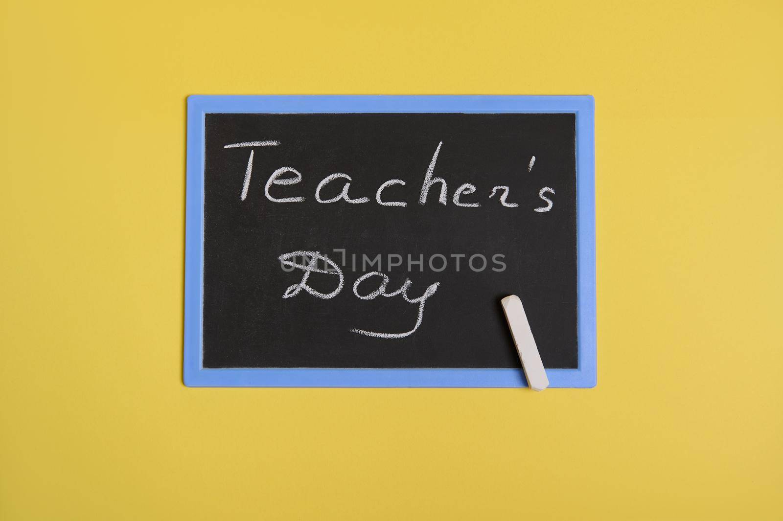Flat lay of a chalkboard with inscription Teachers Day on a yellow background with space for text