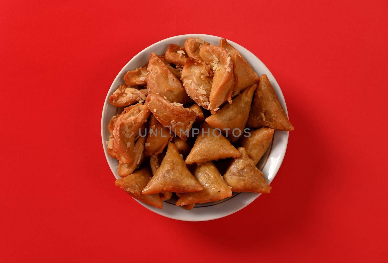 Flat lay photography of delicious and sweet plate full of fresh traditional luxurious Moroccan handmade Brewat sweets, isolated on red background. by artgf