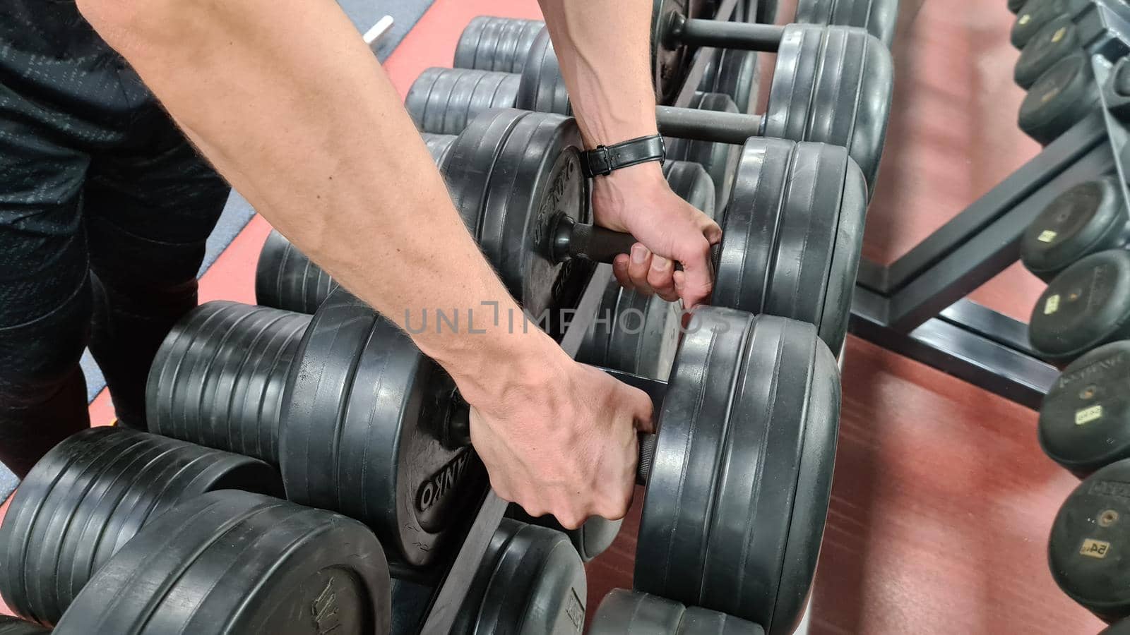 MOSCOW - 2021. Man hands holding black resin dumbbells. . High quality photo