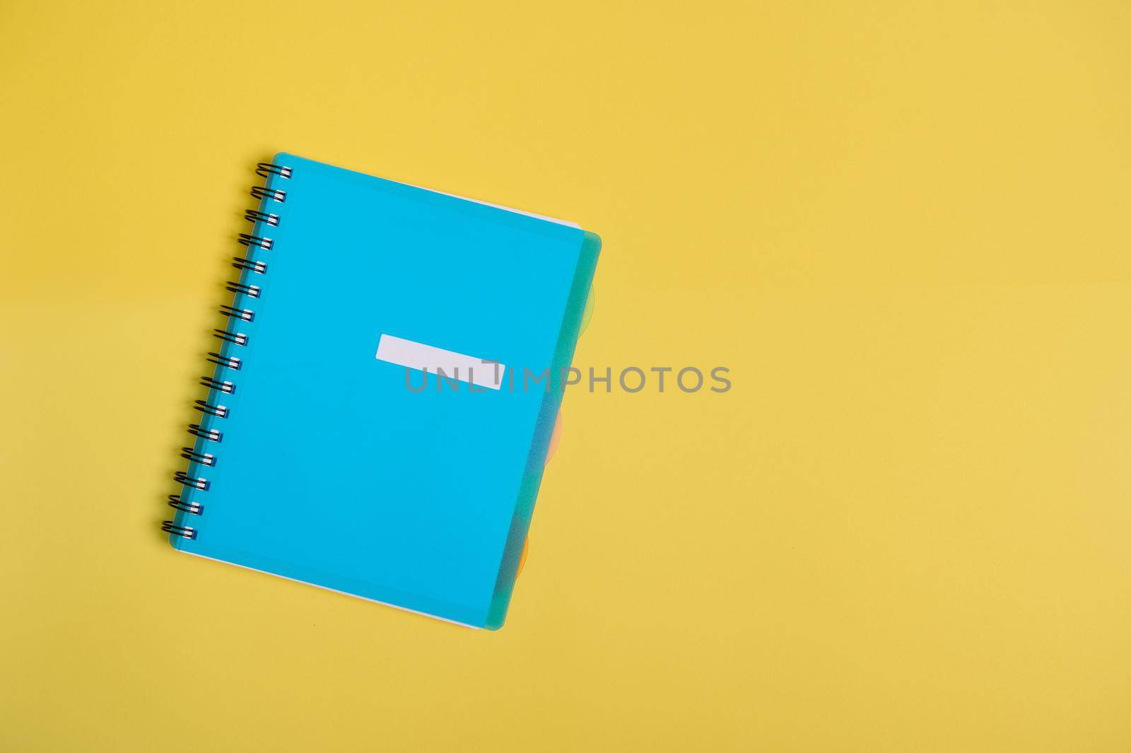 Flat lay of office supply, blue colourful organizer, notepad with empty blank sheet for text, isolated on yellow background with copy space for advertisement