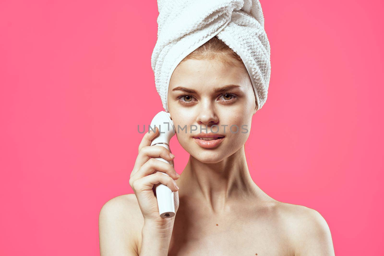 woman with towel on head naked shoulders massager dermatology spa treatments. High quality photo