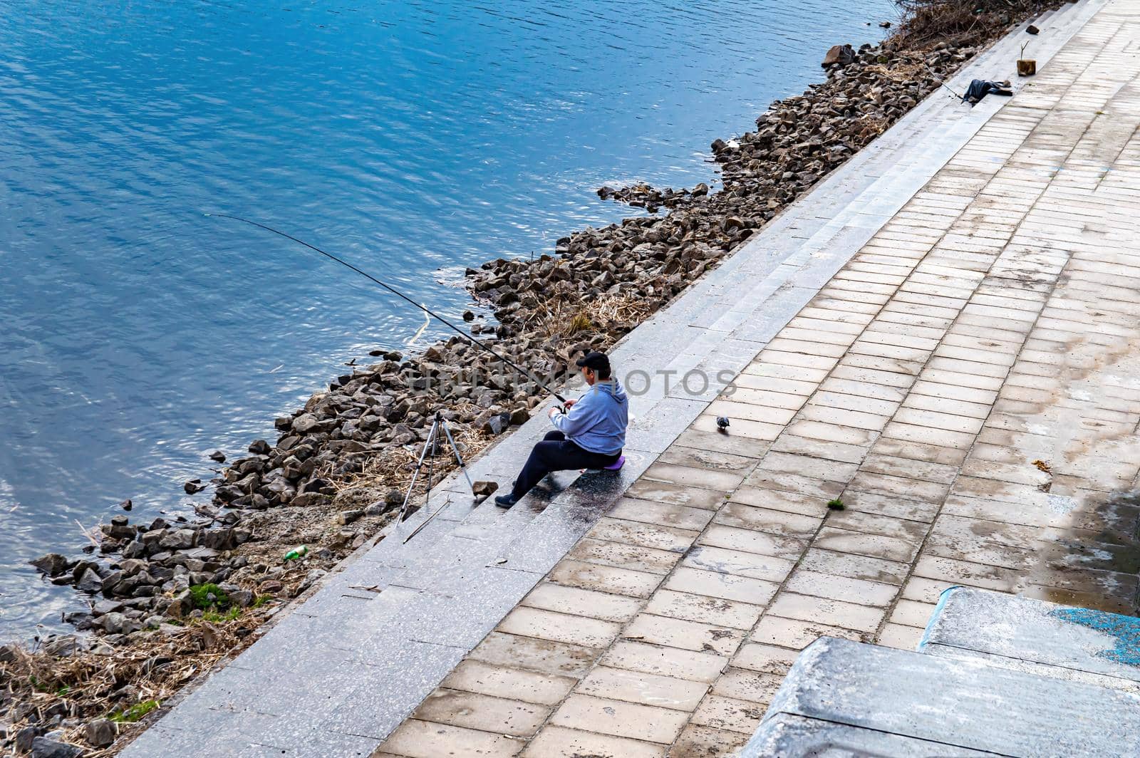 The fisherman catches fish on the embankment of the river. Fishing tackle. The man is a fisherman. Dnepr River. Water flow. City embankment. Fisherman's catch. Leisure activities.