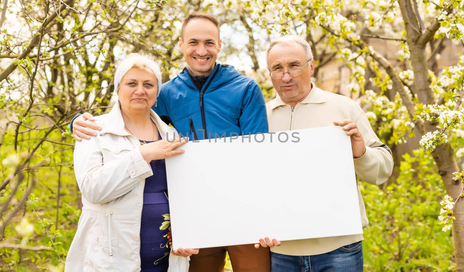 family holds holds photo canvas in the garden by Andelov13