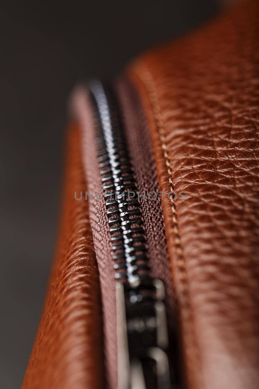 Brown backpack made of textured brown leather on a black stone background. Elegant golden brown women backpack with fashion and rivets. Genuine leather, handmade.