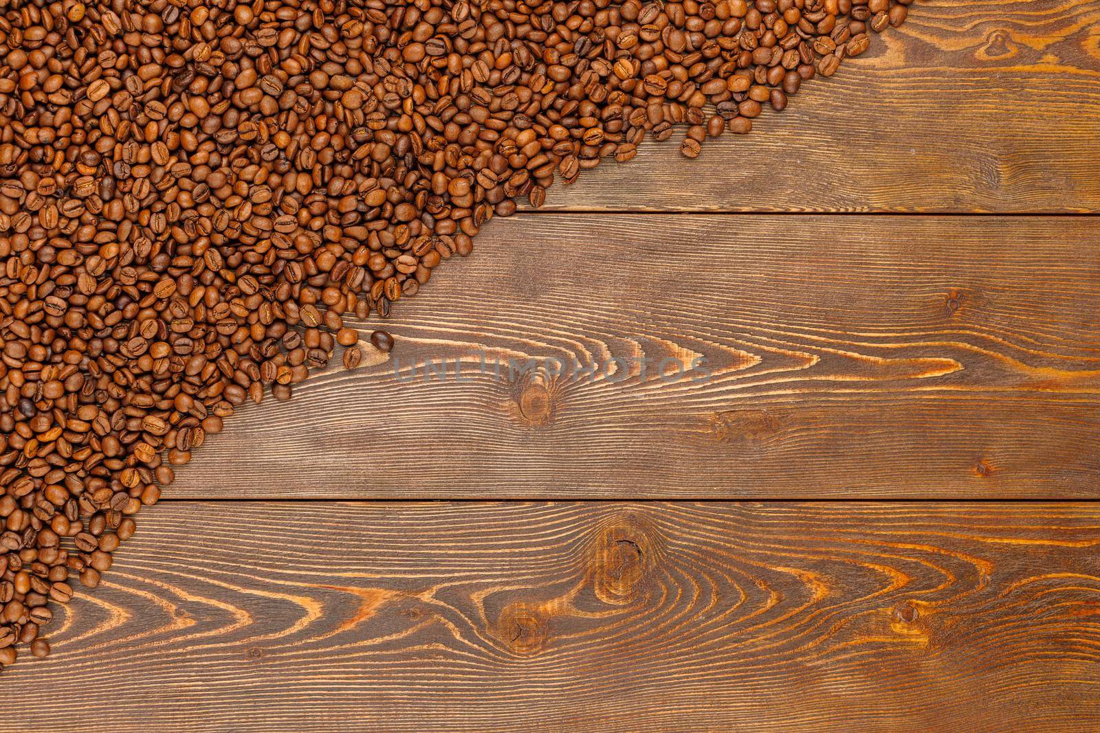 roasted coffee beans laid on brown wooden table surface with copy space