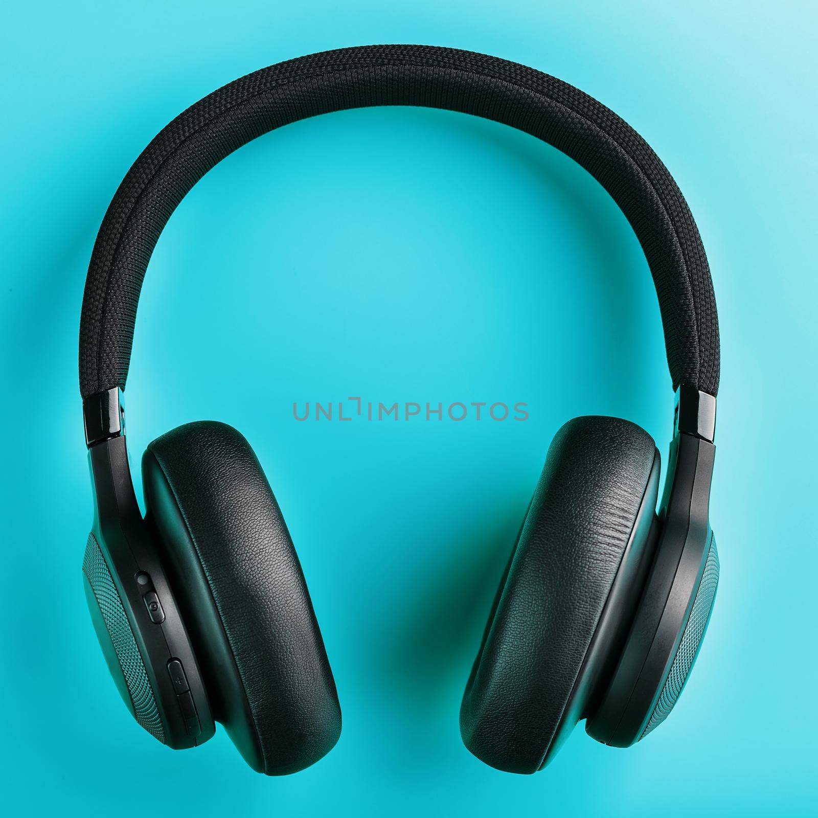 Black wireless headphones on a blue background. Overhead, isolated professional-grade headphones for DJs and musicians. View from above