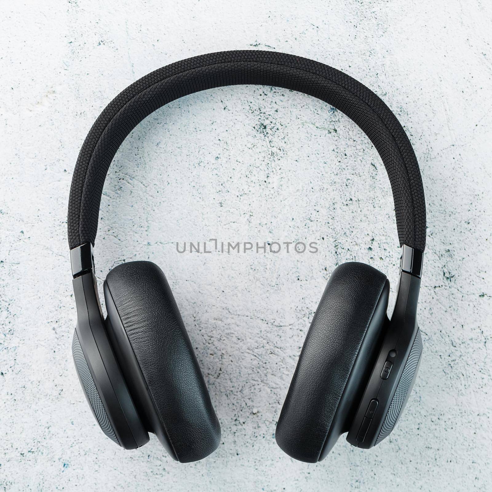 Wireless Black Headphones on a gray stone background. View from above. In-ear headphones for playing games and listening to music tracks by AlexGrec