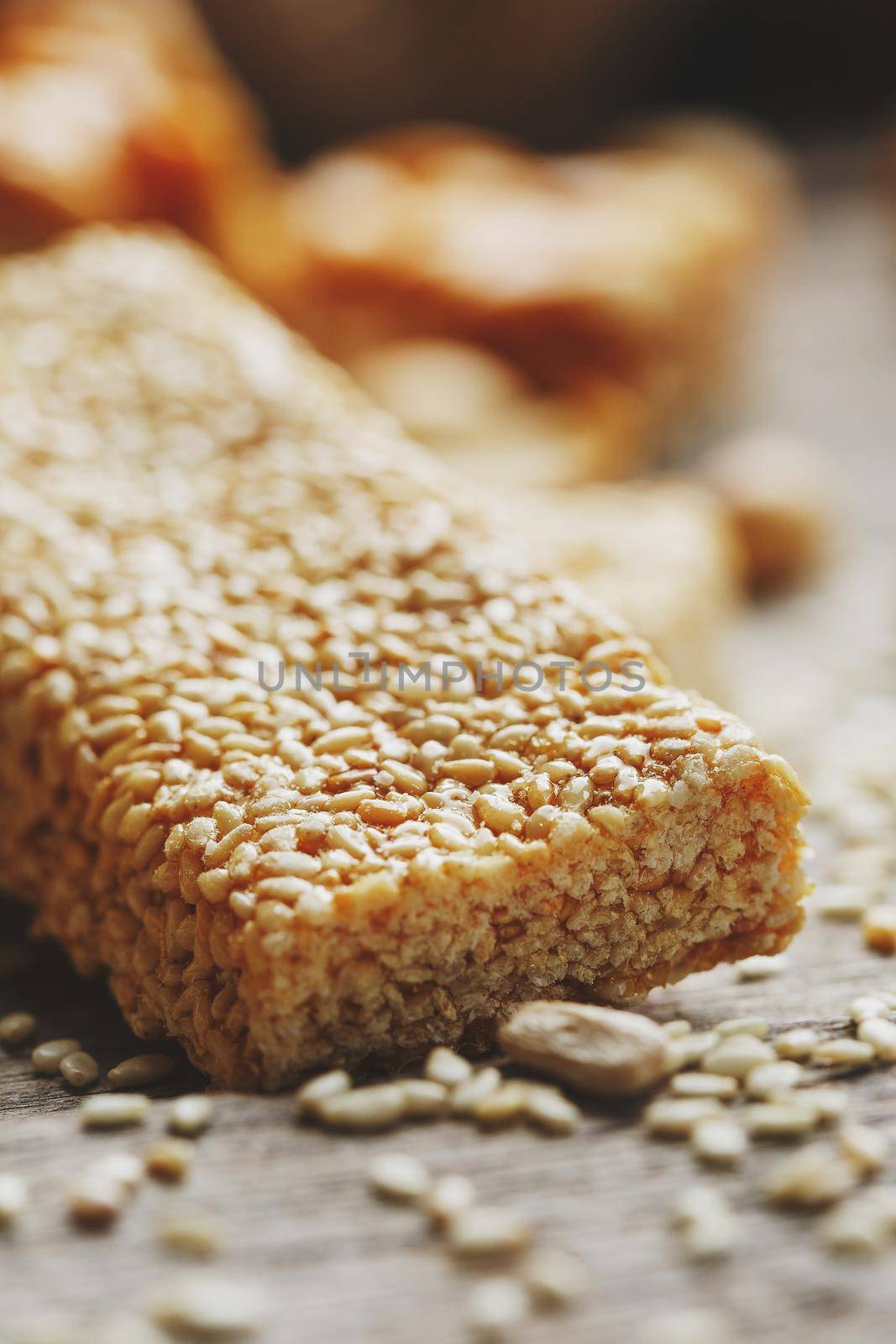 Sweets Bar of sesame on a vintage background with burlap. Delicious oriental sweets Gozinaki from sunflower seeds, sesame and peanuts, covered with honey with a shiny icing. Country style. Macro, vertical frame