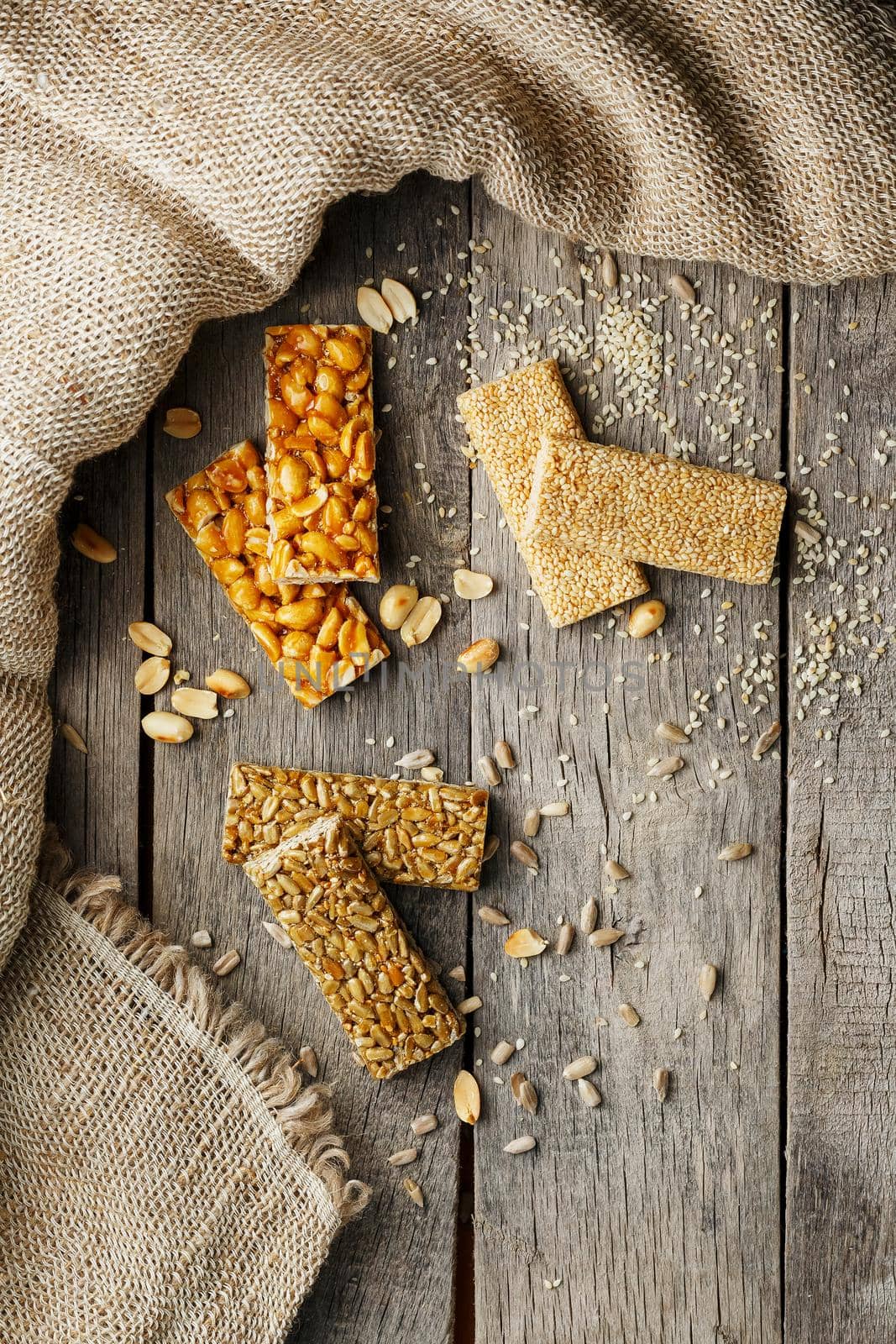 Assorted kozinaki, on old vintage background, with burlap fabric. Country style. Delicious sweets from the seeds of sunflower, sesame and peanuts, covered with shiny glaze. View from above