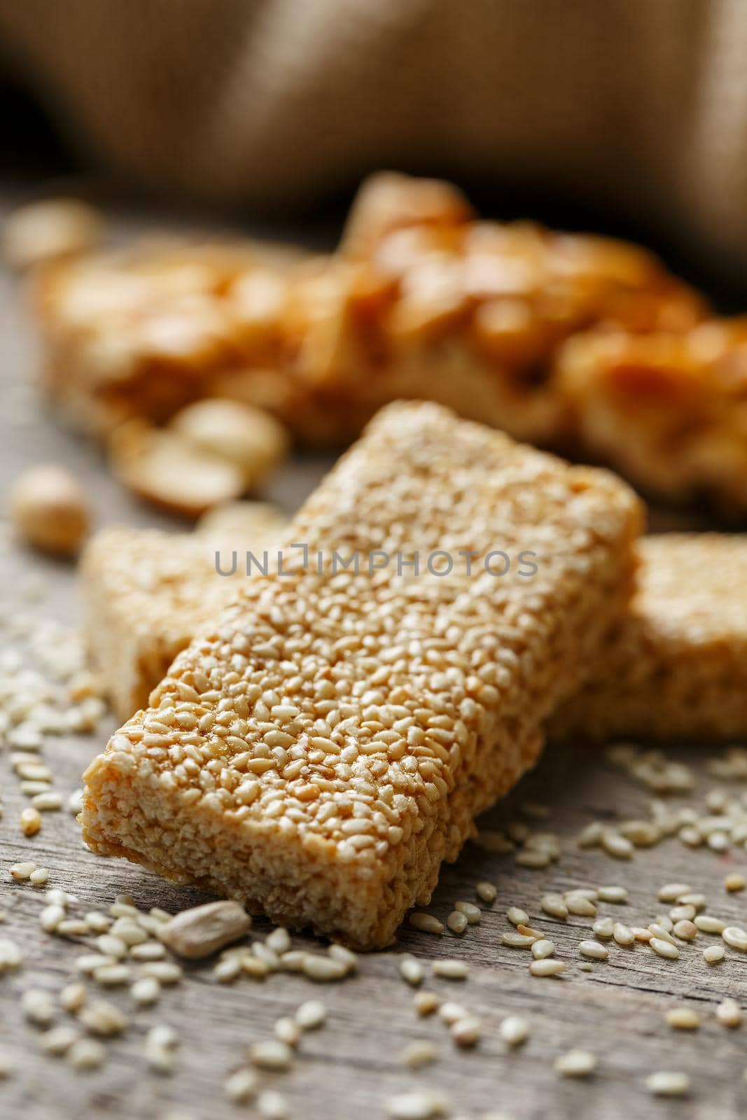 Sesame seed casinos on old vintage background with burlap cloth. Country style. Delicious sweets from seeds of sunflower, sesame and peanuts, covered with shiny glaze. Macro, macro, vertically