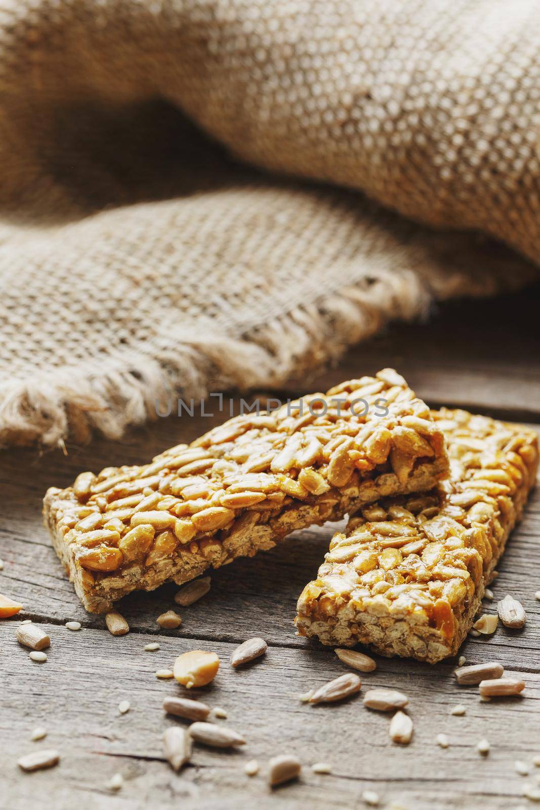 Sweets Bar of sunflower seeds on a vintage background with burlap. Delicious oriental sweets Gozinaki from sunflower seeds, sesame and peanuts, covered with honey with a shiny icing. Macro, vertical frame