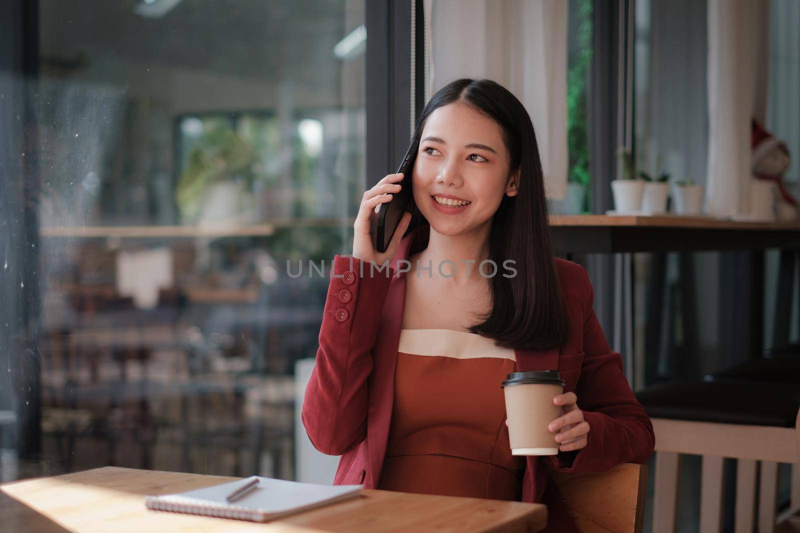 Businesswoman discussing with her team by mobile phone while relexing at coffee shop. Finance concept. by itchaznong