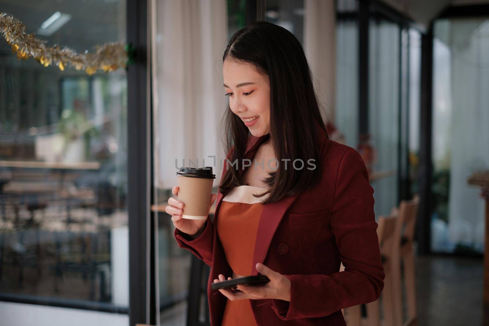 Smiling and happy asian businesswoman looking at mobile phone. Finance and Accounting concept.