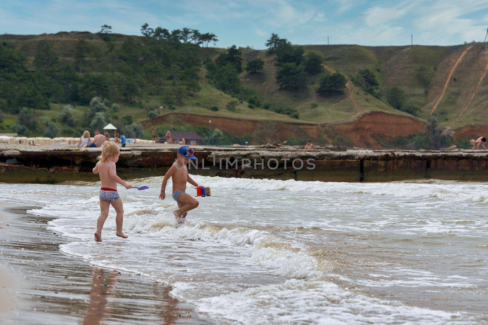 Two little boys are playing on the seashore. Children playing on the beach