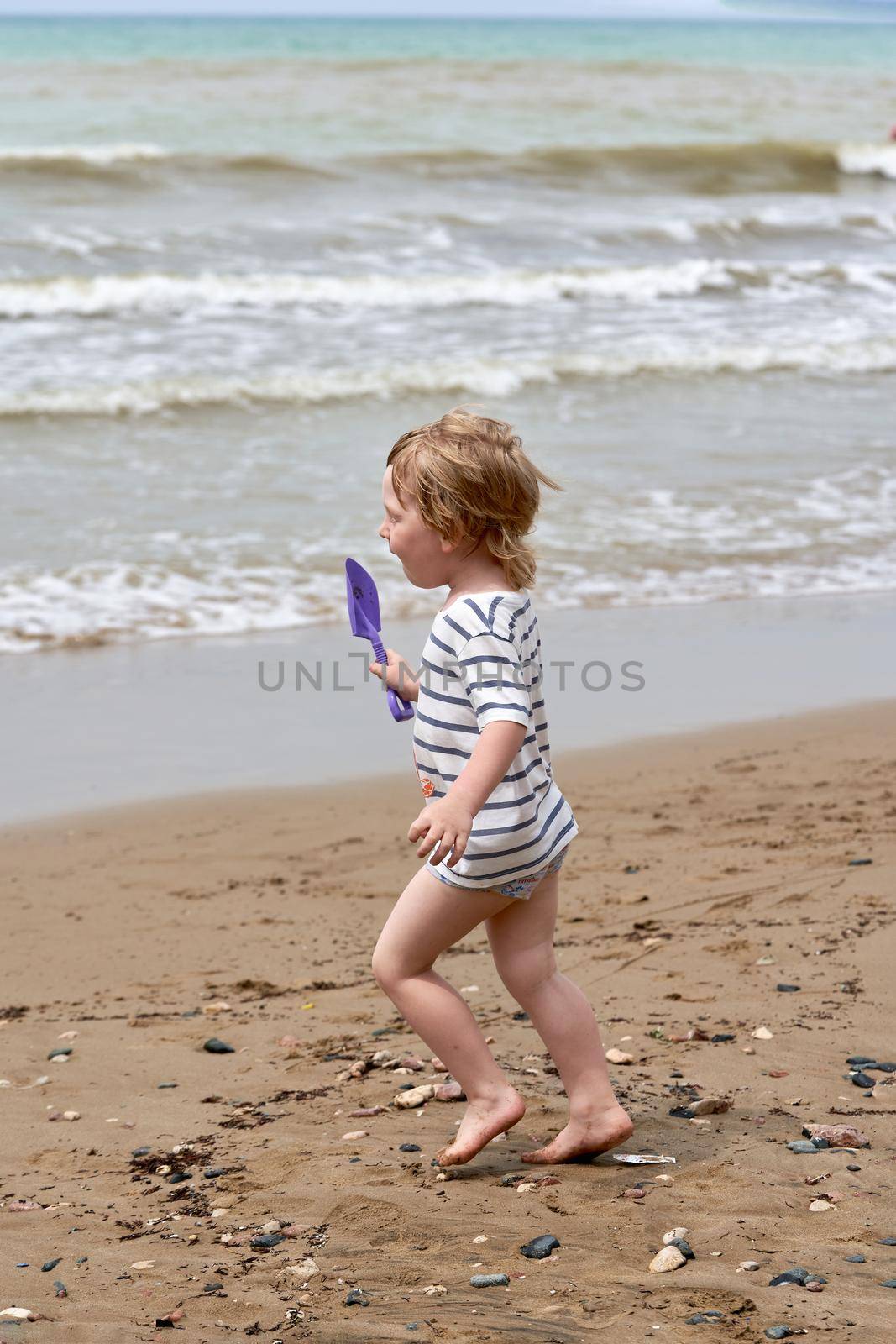 A little boy runs along the sandy beach along the seashore. Child resting on the sea