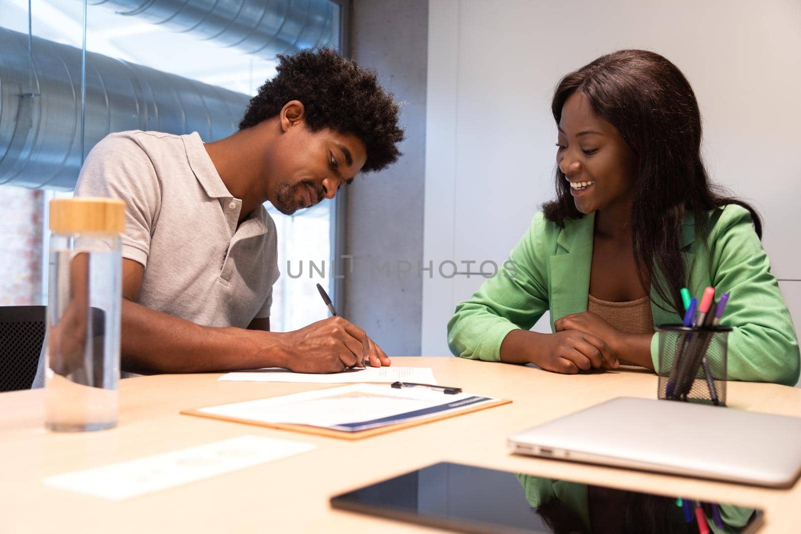 Two african american people signing contract in office. by Hoverstock