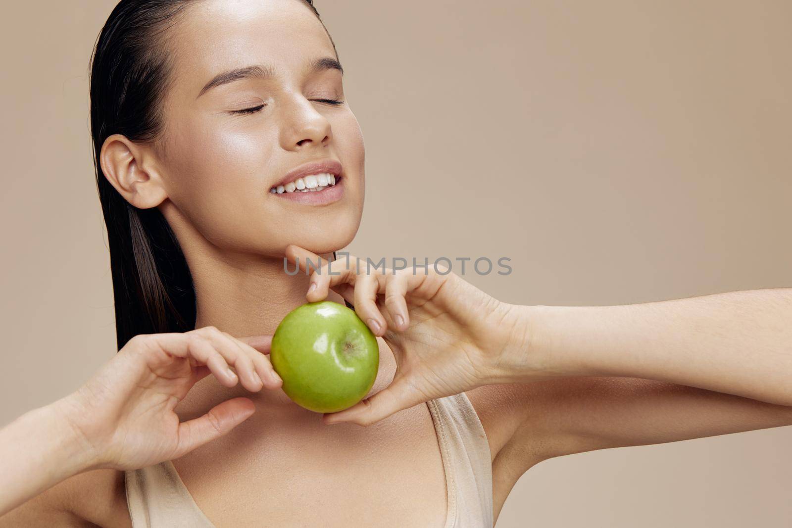 woman with a green apple smile beige background. High quality photo