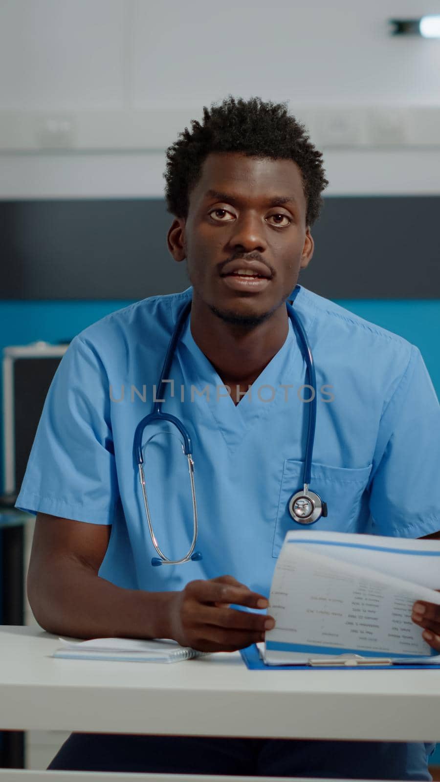 Man nurse talking on video call technology while sitting at desk by DCStudio