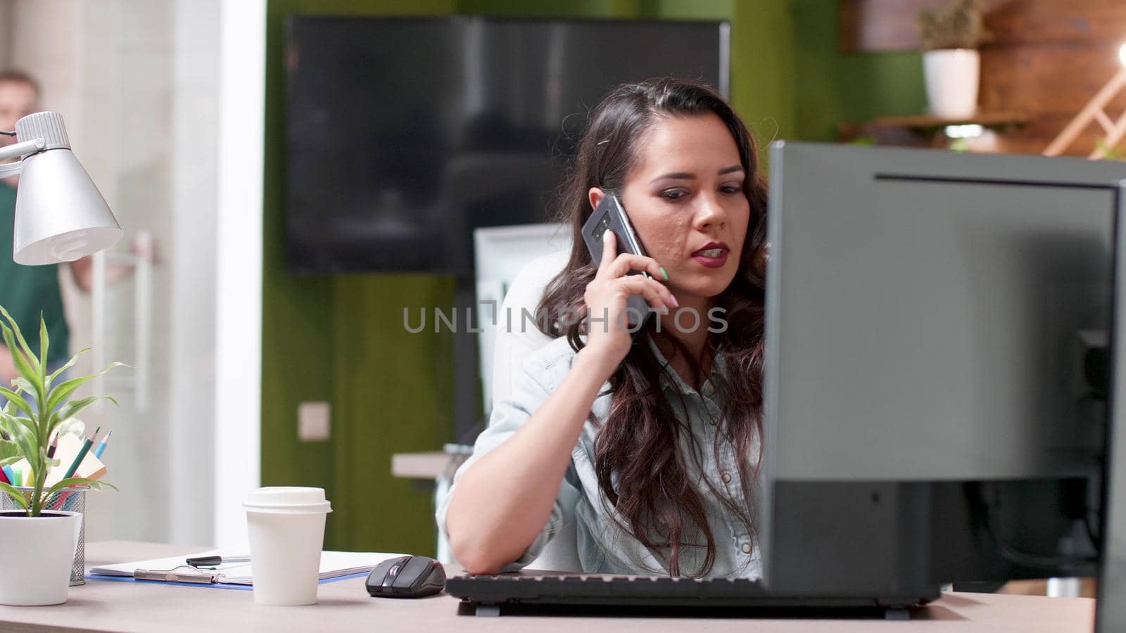 Executive manager sitting at table talking at modern smartphone with remote entrepreneur discussing management strategy. Successful businesswoman working at business presentation in startup office