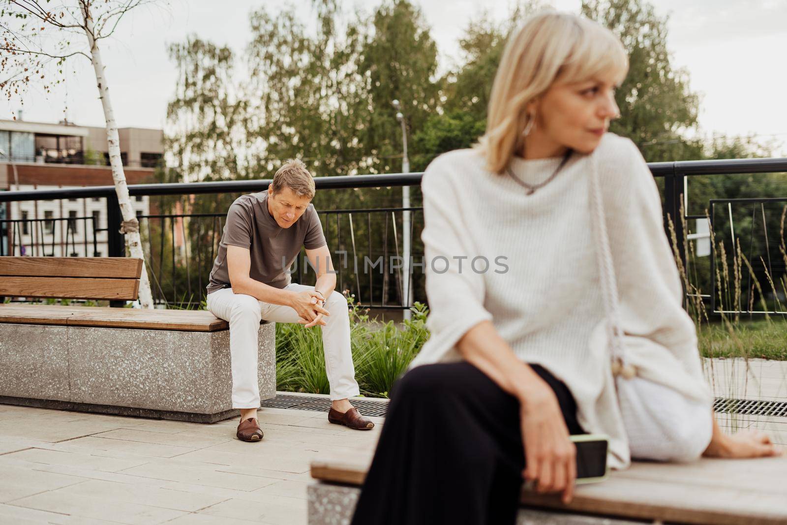 Mature couple in a bad mental condition after a quarrel outdoors. Adult couple man and woman trying to overcome anxiety and disorder after a break-up scene.