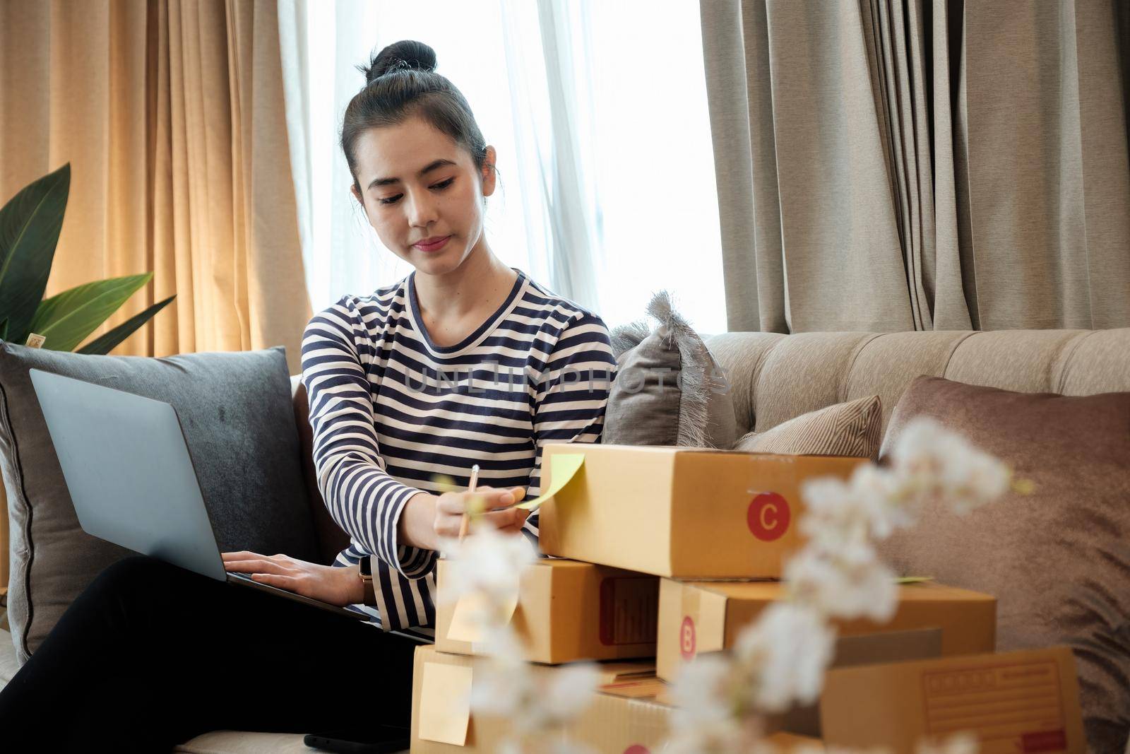 Startup small business SME, Entrepreneur owner using laptop computer and checking online purchase shopping order to preparing pack product box. Selling online ideas concept