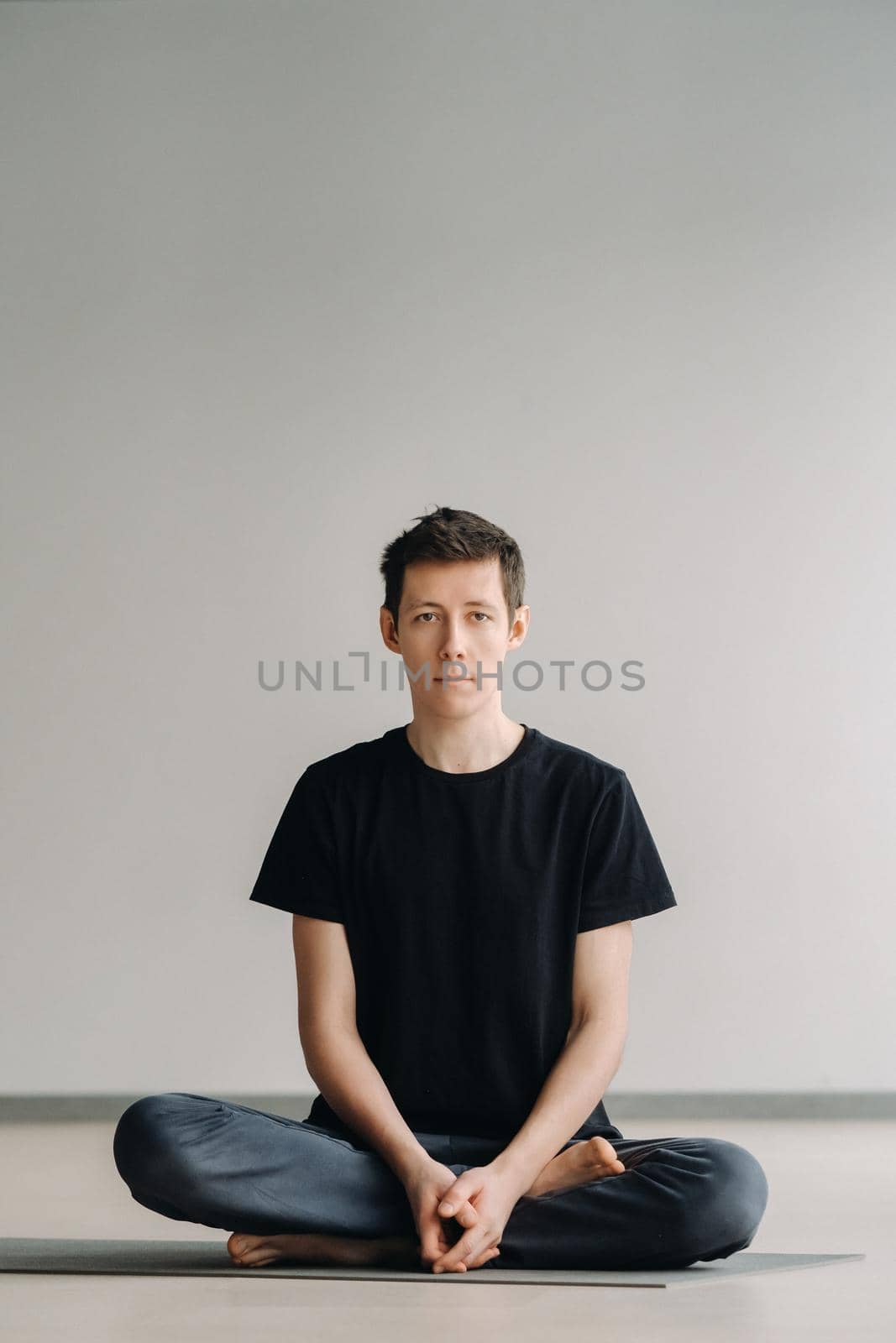 A male athlete in a black T-shirt is sitting in the gym before training and resting by Lobachad