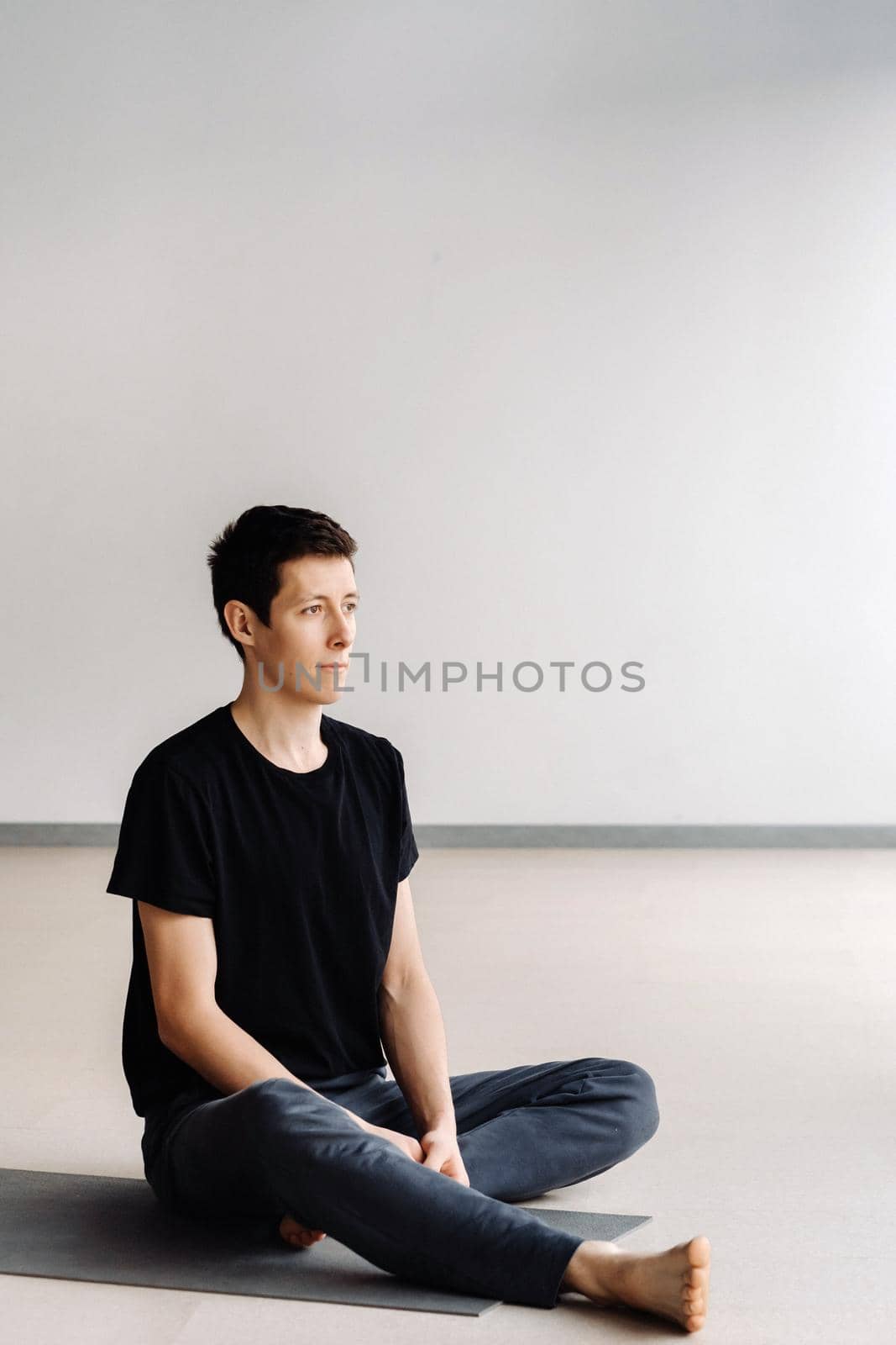 A male athlete in a black T-shirt is sitting in the gym before training and resting by Lobachad